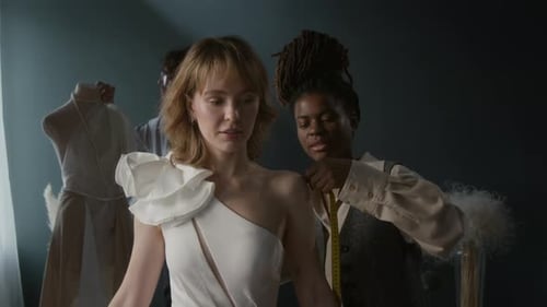 Jovem costureira negra fazendo medições e conversando com a noiva