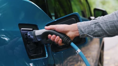 Nahaufnahme Mann, der ein Elektroauto oder Elektrofahrzeug an die grüne Ladestation anschließt. Speichern Sie die ökologische Alternative e
