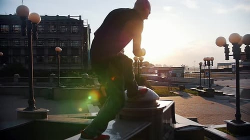Man does acrobatic flips in the city at sunrise