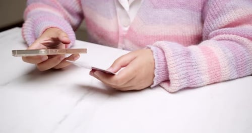 Close-up woman's hand holds a smartphone and use a mockup Bank credit card for online shopping servi