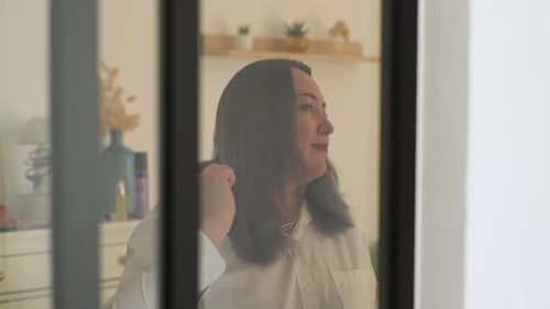 Closeup of Brunette Female Brushing Hair Looking in Mirror Happy Plus Size Young Beautiful Woman