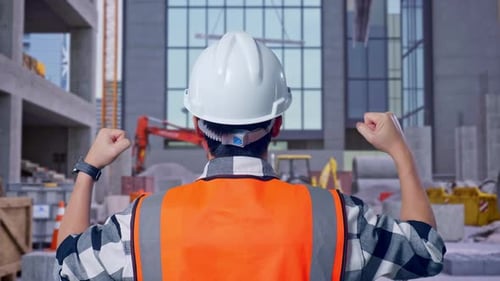 Back View Of A Male Engineer Raising His Hands Celebrating While Working at Construction Site