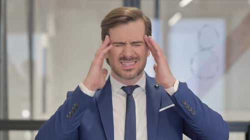Man in Blue Suit with Headache in Office