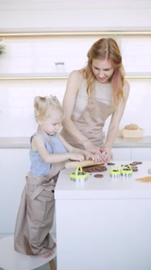 Vidéo verticale Une mère et sa fille aiment cuisiner ensemble dans une cuisine lumineuse tout en préparant des biscuits