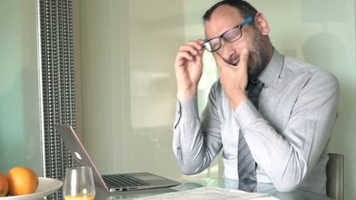 Tired Man Using Laptop While Sitting at Table