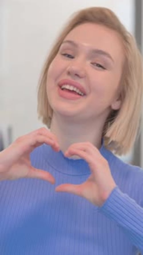 Smiling Young Woman Makes Heart Shape With Hands