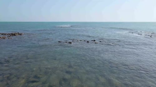 Seascape of rocky coast with vast blue ocean in a tropical island. Gentle waves breaking on corals.