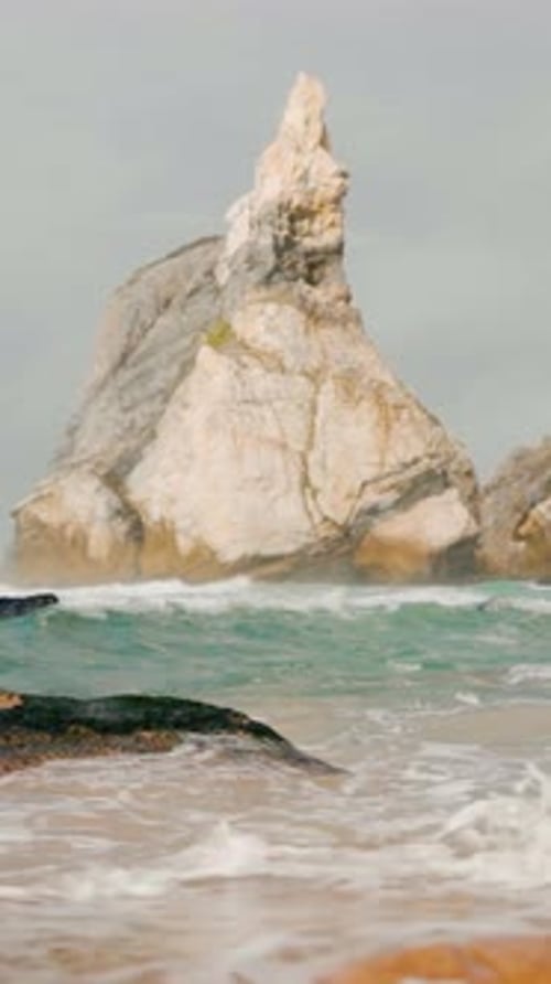 Vidéo verticale de vagues s'écrasant sur des rochers sur le rivage de la plage d'Ursa. Des images au ralenti.