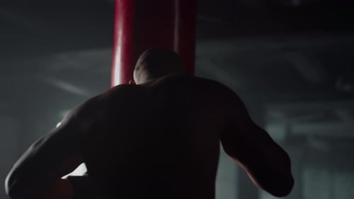 Muscular Sportsman Punch Bag in Sport Club. Professional Male Boxer Boxing Training