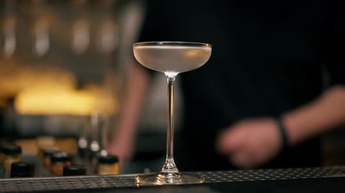 in a Night Bar of an Expensive Establishment the Bartender Uses a Hookah to Smoke a Glass of Martini