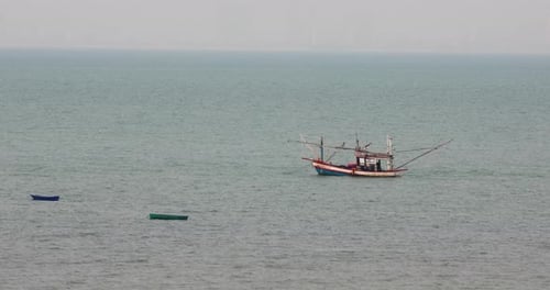 Zwei kleine Boote und ein thailändisches Fischereifahrzeug ankerten in den Gewässern vor der Küste von Pattaya, Thailand.