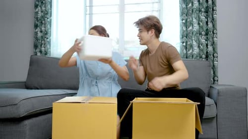 Asian young cute couple unpacking their stuff together in new house on moving day.