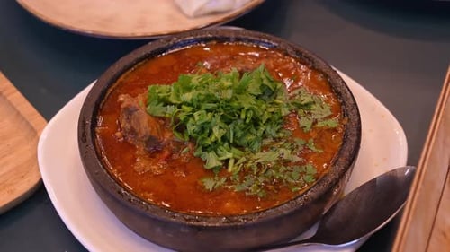 Olla de barro con plato humeante adornado con cilantro