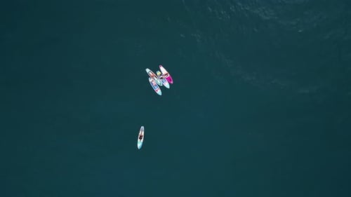 Aerial View People Paddling on a Stand Up Board on Turquoise Water Surfers Training on SUP Board in