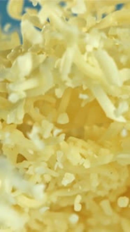 Shredded Cheese Flies Up On a Blue Background Filmed on a Highspeed Camera at 1000 Fps