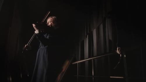Woman Plays Violin On Darkly Lit Stage