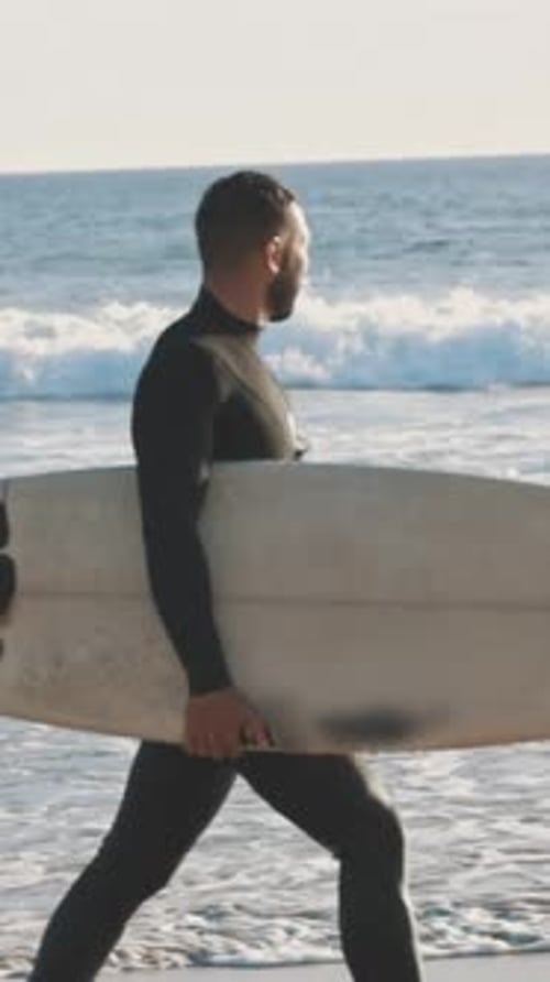 Surfer Walking on the Beach with a Large Surfboard