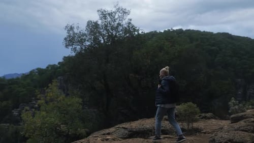A Young Female Tourist Runs Up to the Cliff of a Canyon or Mountain