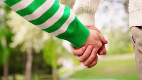 Couple Holding Hands in a Green Park