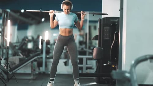Fit Woman Performing Barbell Squats at the Gym