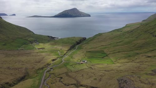 Flight over a road and small villages on Faroe Islands towards Atlantic Ocean