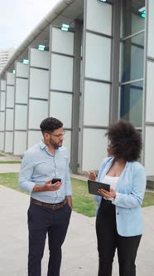 two diverse Business people discussing a project while walking outside office building