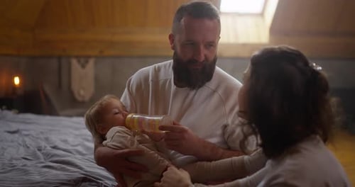 Un homme brun avec une barbe communique avec sa femme brune et tient sa petite fille dans son
