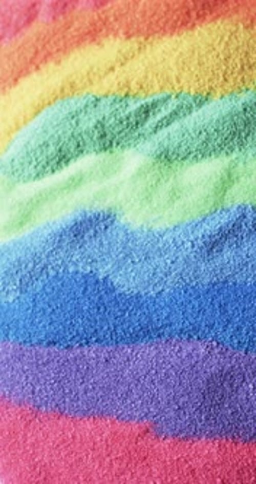 Vertical video of close up of rainbow coloured sand grains and copy space background