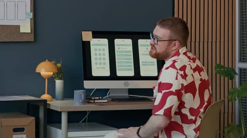 Man Discussing Mobile App Design on Screen with Black Female Colleague at Office