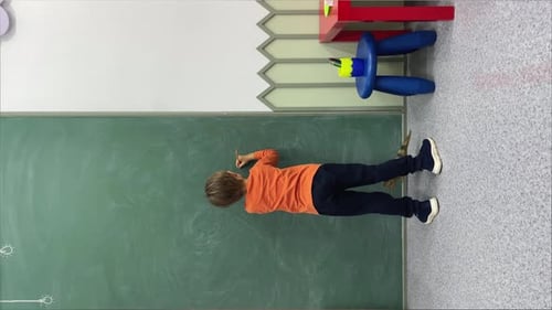 Child Writing on Chalkboard in Classroom Setting