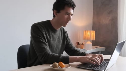 Man Typing on Laptop at Desk