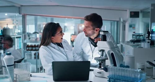 Scientists Collaborating Using Microscope in Bright Lab