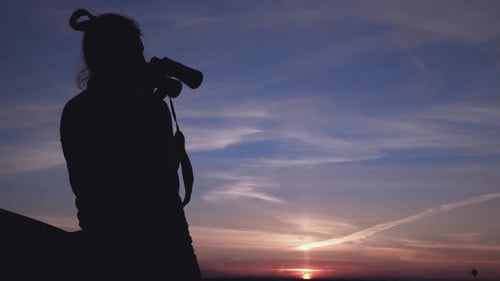 Silhouette Watches a Colorful Sunset with Camera