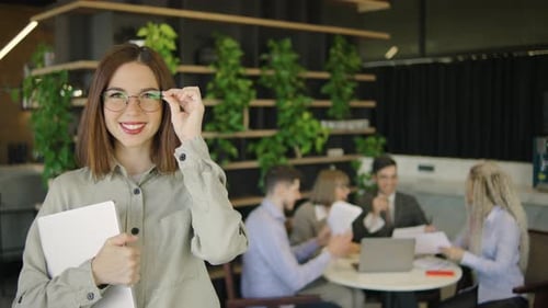 Smiling Woman Holding Laptop in Modern Office Setting