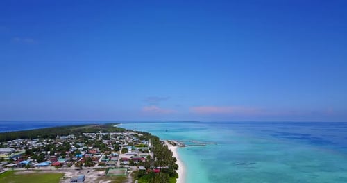 Wide panoramic birds eye view over Maldives island. Stunning coastline and village beneath sunny blu
