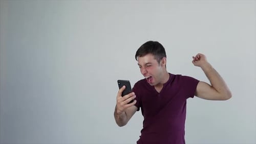 Man Celebrating While Looking at His Smartphone