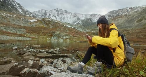 Hiker Using Smartphone Near Mountain Lake Enjoying Autumn Landscape