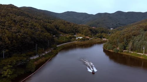 Backwards aerial view of a speedboat with jet skier starting seen from the front