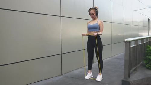 Young Sport Woman Athlete Exercising Outdoors in City with Resistance Band Enjoying Active Lifestyle