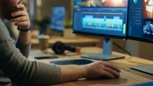 Male Videographer Edits and Cuts Footage and Sound on His Personal Computer with Two Displays. His