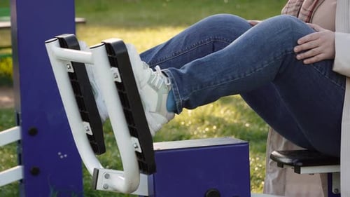 Woman Using Leg Press Machine in Park