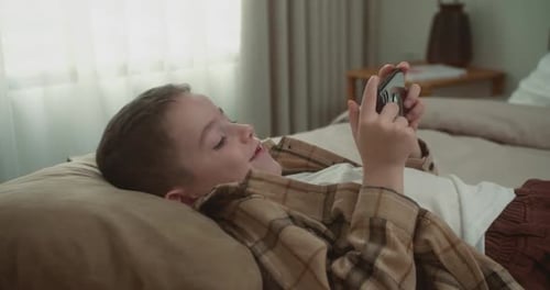 Child Plays Game on Smartphone in Bedroom