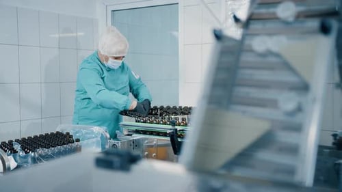 Medical Worker Sorting Vials on Conveyor Belt in Lab