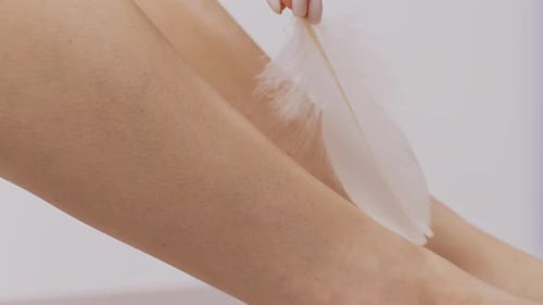Woman Touches Leg with White Feather