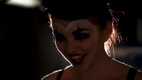 Woman with clown makeup smiles in the darkness