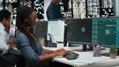 Woman Working on Multiple Computer Screens in Office