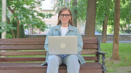 Young Woman Using Laptop on Park Bench