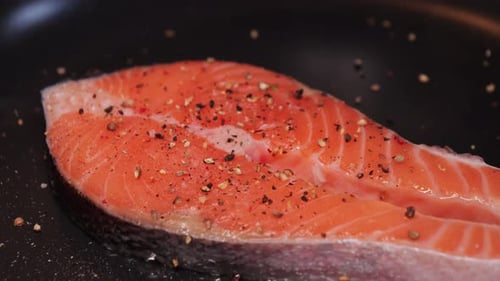 Salmon steak seasoned on a frying pan close-up