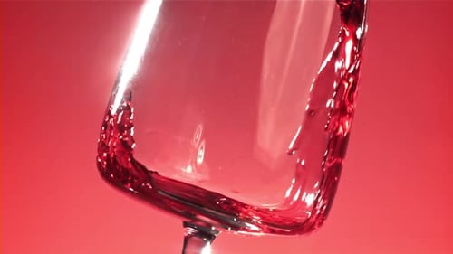 Red Wine is Poured Into a Glass On a Pink Background Filmed on a Highspeed Camera at 1000 Fps