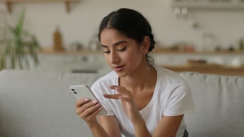 Woman Using Smartphone While Relaxing at Home